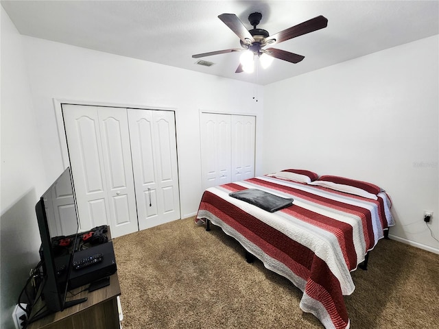 bedroom with baseboards, visible vents, a ceiling fan, dark colored carpet, and multiple closets