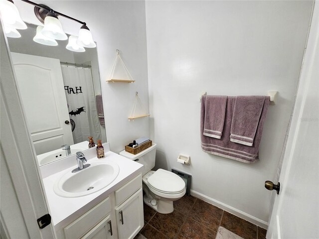 bathroom with toilet, baseboards, and vanity