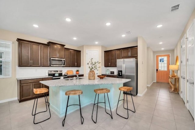 kitchen featuring a breakfast bar area, stainless steel appliances, a kitchen island with sink, and sink