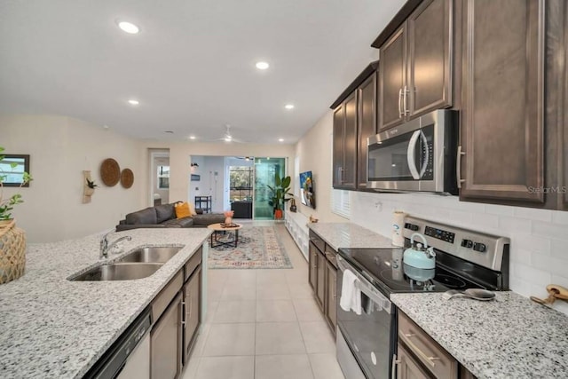 kitchen with sink, light tile floors, light stone counters, appliances with stainless steel finishes, and tasteful backsplash