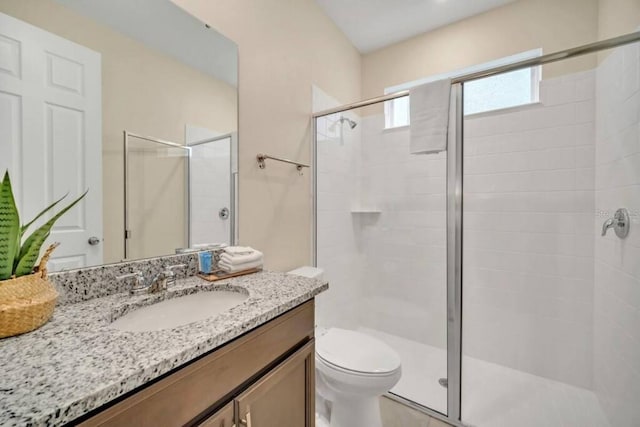 bathroom with a shower with door, oversized vanity, and toilet