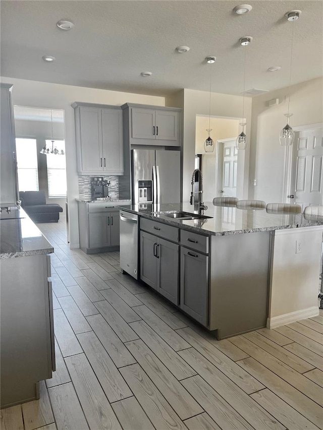 kitchen featuring hanging light fixtures, gray cabinets, stainless steel appliances, and sink