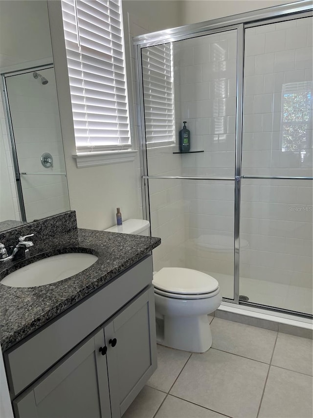 bathroom featuring vanity, toilet, tile patterned flooring, and a shower with door