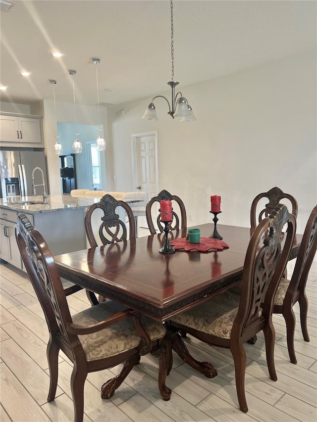 dining space with sink, a notable chandelier, and light wood-type flooring