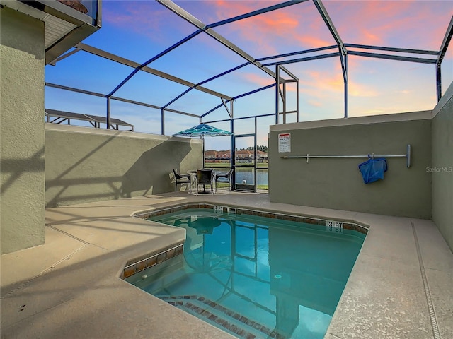 pool at dusk featuring a patio and glass enclosure