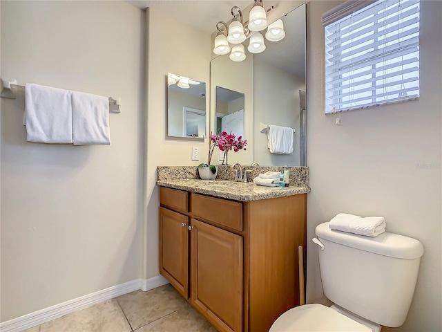 bathroom featuring toilet, vanity with extensive cabinet space, tile flooring, and a notable chandelier