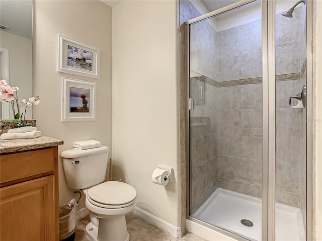 bathroom featuring tile floors, toilet, vanity, and a shower with shower door