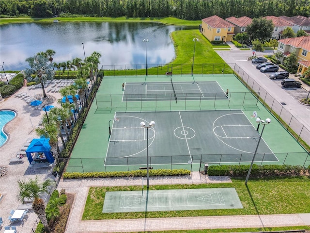 view of sport court with a water view, tennis court, and a yard