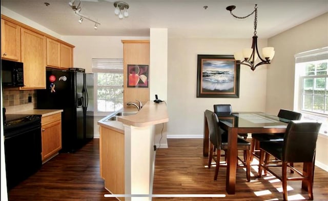 kitchen featuring plenty of natural light, a notable chandelier, black appliances, sink, and decorative light fixtures