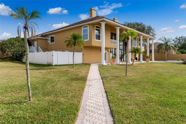 view of front of house with a front lawn, fence, a chimney, and stucco siding