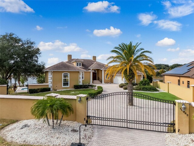 view of front facade featuring a gate, decorative driveway, a fenced front yard, and stucco siding