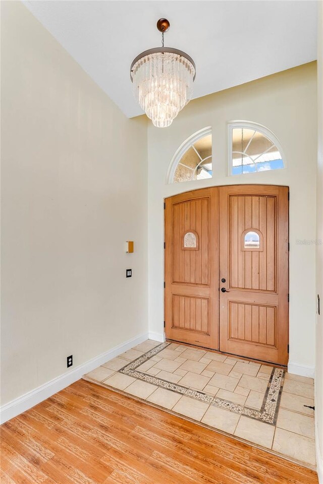 foyer entrance with light wood-style floors, baseboards, and a chandelier