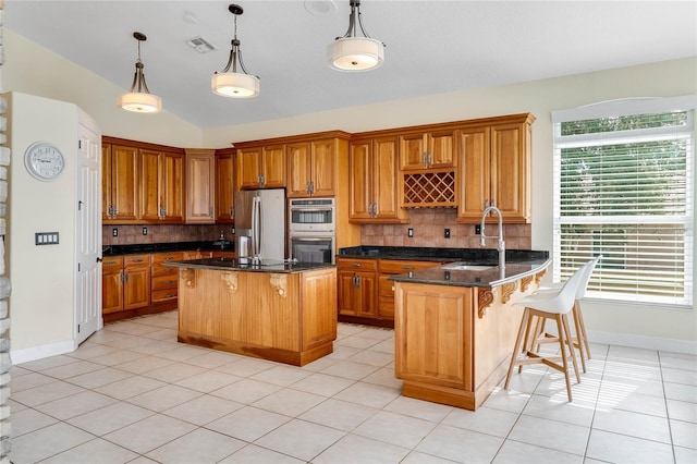 kitchen featuring a kitchen bar, visible vents, appliances with stainless steel finishes, and brown cabinets