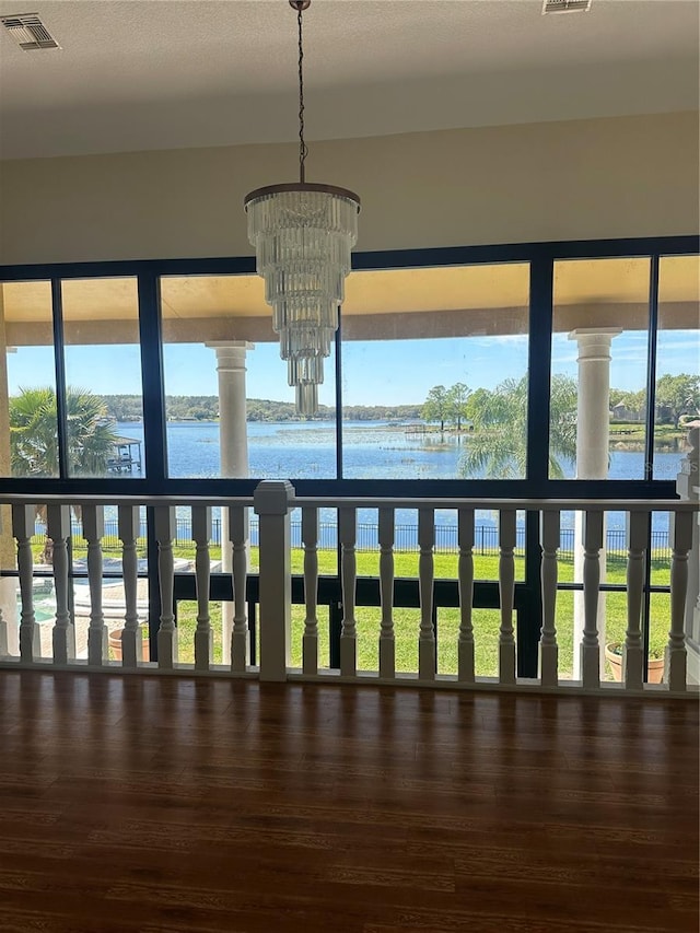 interior space featuring a chandelier, visible vents, wood finished floors, and a water view