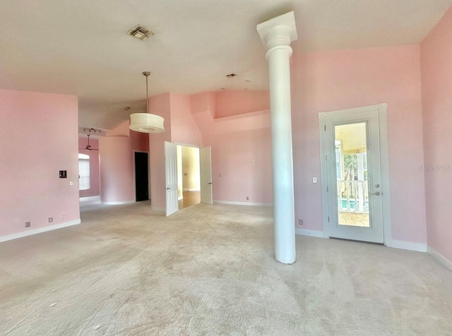 unfurnished living room with high vaulted ceiling, visible vents, ornate columns, and light carpet