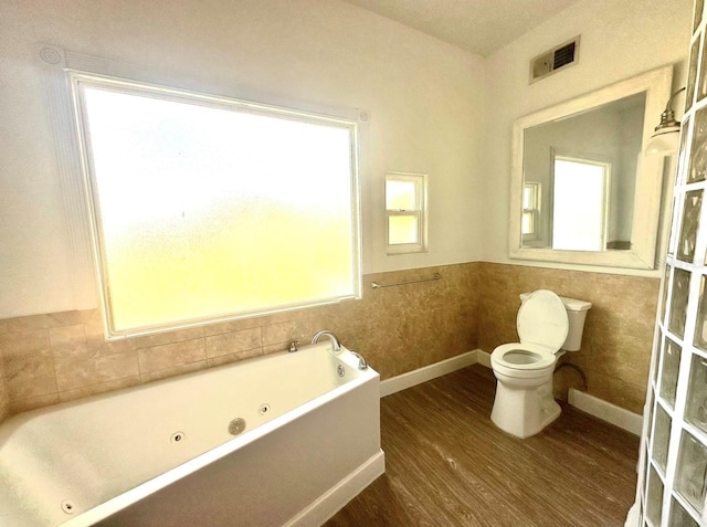 full bathroom with visible vents, toilet, wood finished floors, baseboards, and a whirlpool tub