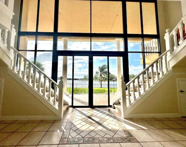 doorway to outside featuring expansive windows, stairway, baseboards, and tile patterned flooring