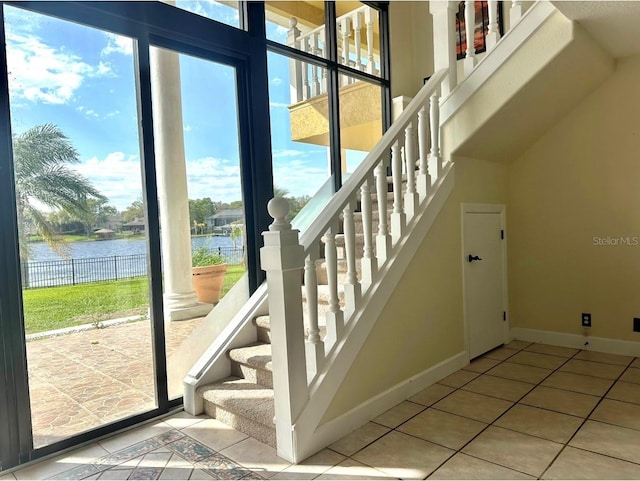 stairs featuring tile patterned floors, baseboards, and a water view