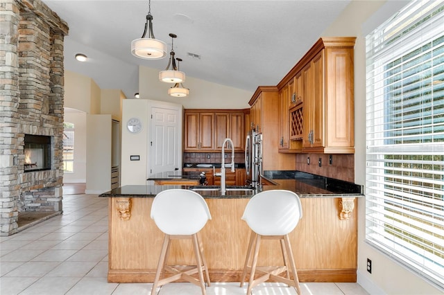 kitchen with light tile patterned floors, vaulted ceiling, a fireplace, and a sink