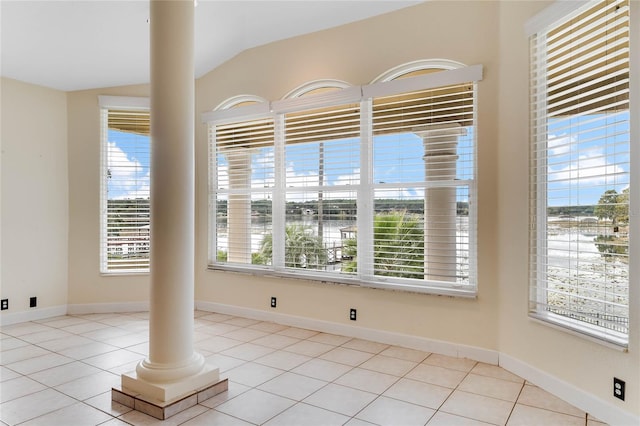 empty room with light tile patterned flooring, baseboards, and ornate columns