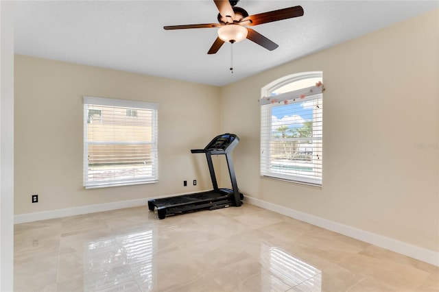 workout room featuring baseboards and ceiling fan