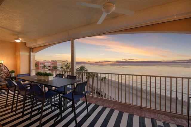 deck at dusk featuring a water view and ceiling fan