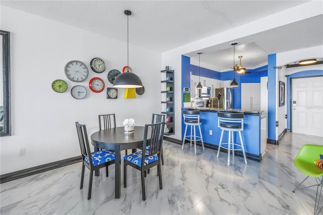 dining space featuring marble finish floor, crown molding, a ceiling fan, a textured ceiling, and baseboards