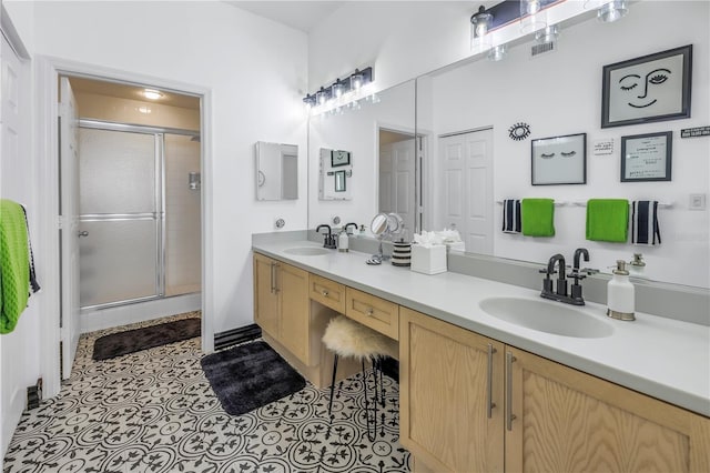 full bathroom with double vanity, a stall shower, and a sink