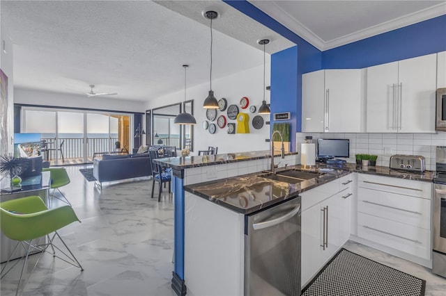 kitchen with a peninsula, white cabinetry, a sink, and decorative light fixtures