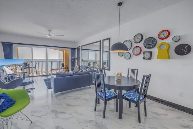 dining room with a textured ceiling, marble finish floor, ceiling fan, and baseboards