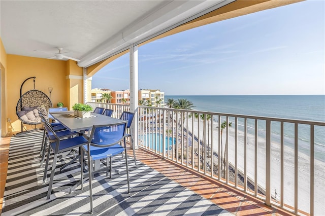 balcony with a ceiling fan, a view of the beach, a water view, and outdoor dining space