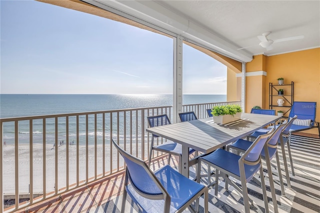 balcony featuring outdoor dining space, a water view, ceiling fan, and a beach view