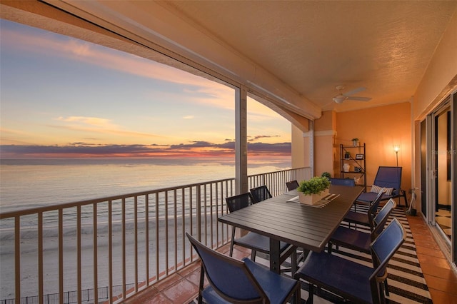 balcony with a ceiling fan, outdoor dining area, and a water view