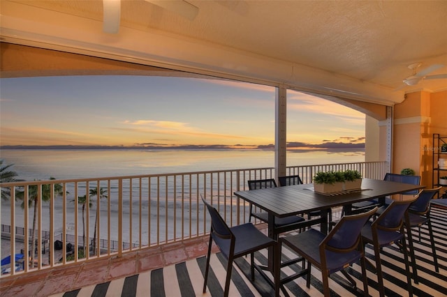 balcony featuring a water view, ceiling fan, and outdoor dining area