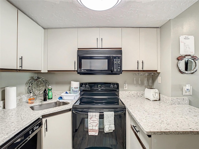 kitchen with light stone counters, white cabinetry, sink, and black appliances