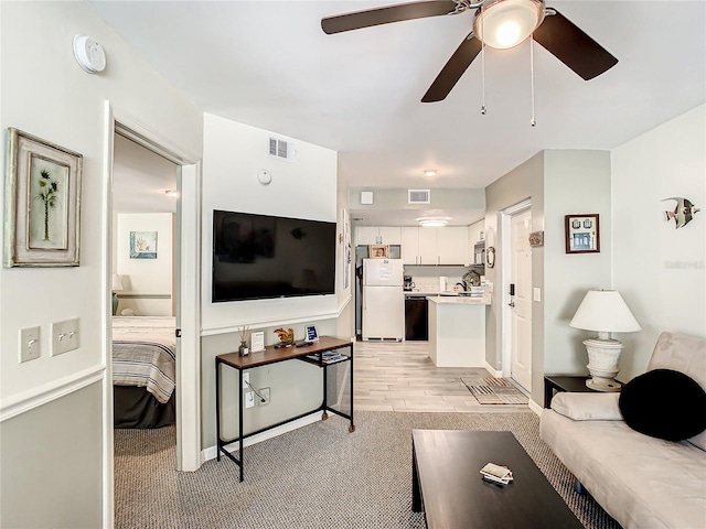 carpeted living room with ceiling fan