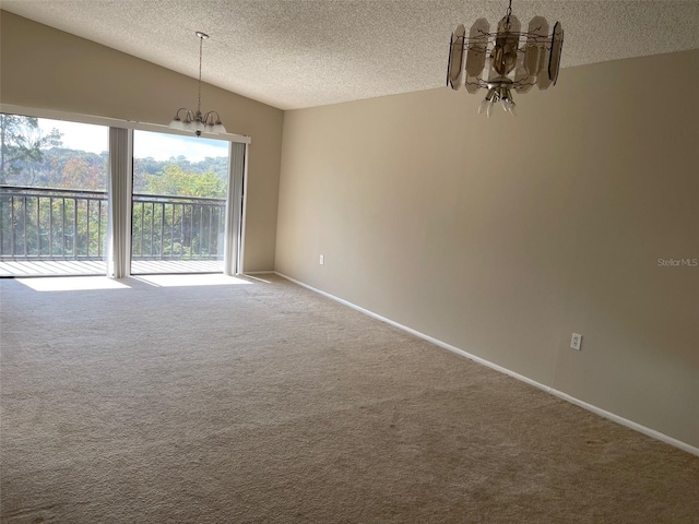 carpeted spare room featuring a notable chandelier and a textured ceiling