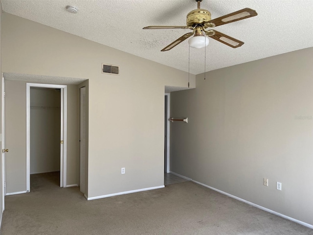 unfurnished bedroom with lofted ceiling, visible vents, a textured ceiling, and carpet floors