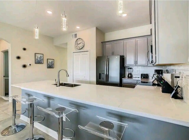 kitchen with a kitchen bar, backsplash, sink, and stainless steel appliances