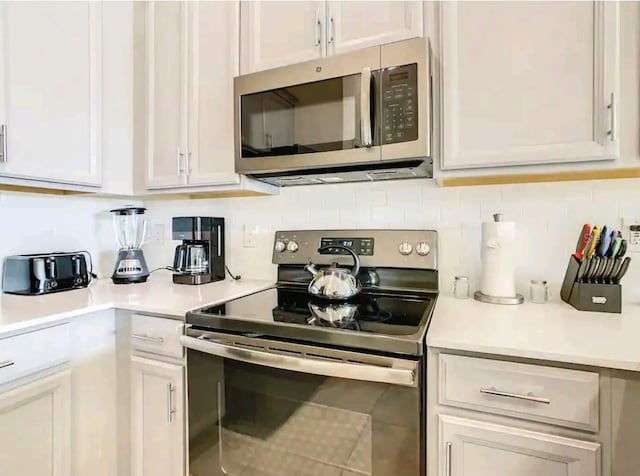 kitchen with tasteful backsplash, stainless steel appliances, and white cabinetry