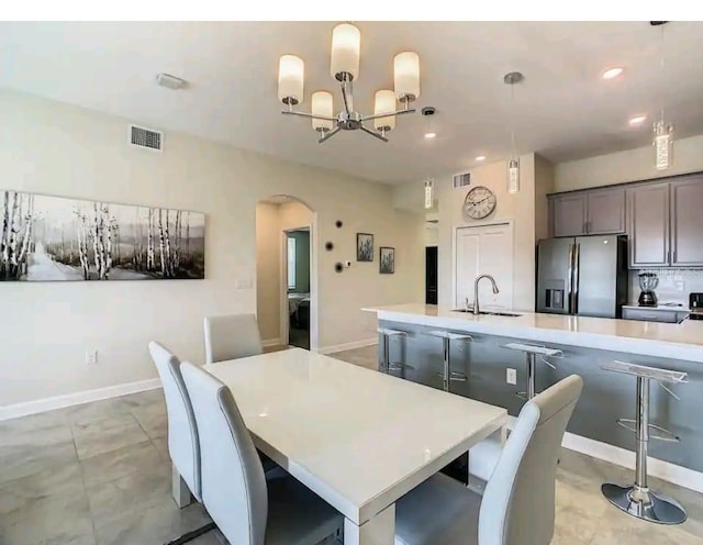 dining space with light tile flooring, sink, and a notable chandelier