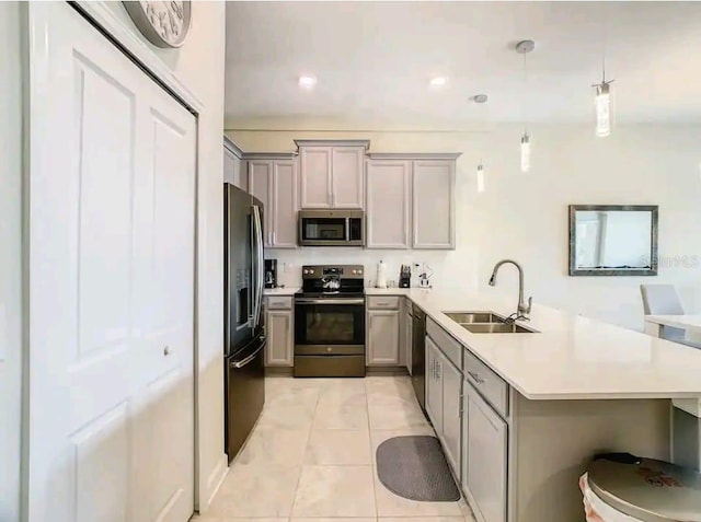 kitchen featuring light tile flooring, a kitchen bar, gray cabinets, appliances with stainless steel finishes, and sink