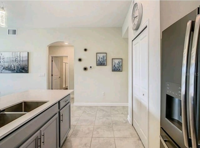 kitchen with gray cabinets, stainless steel refrigerator with ice dispenser, and light tile flooring