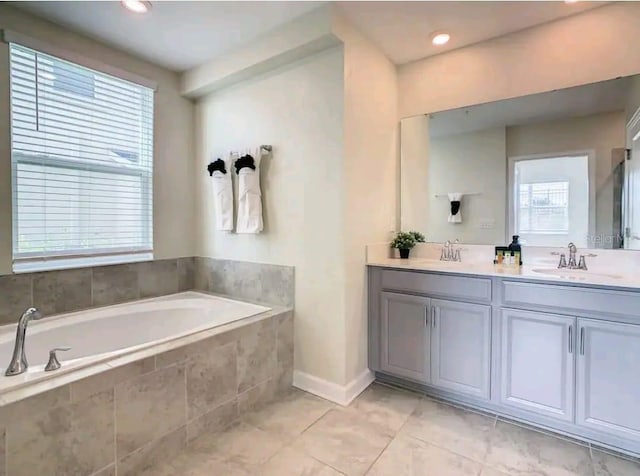 bathroom with tiled tub, dual vanity, and tile flooring