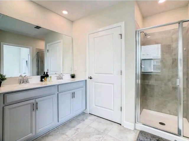 bathroom featuring a shower with door, tile floors, and double sink vanity