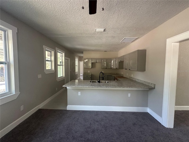 kitchen featuring kitchen peninsula, dark colored carpet, a textured ceiling, and sink