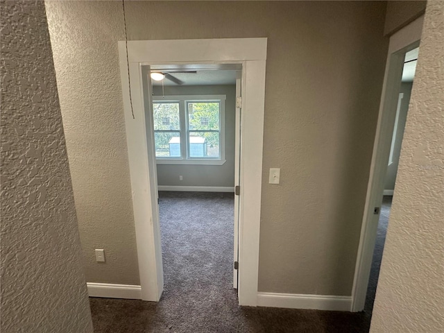 hallway featuring dark colored carpet