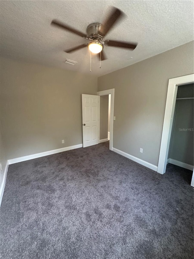 unfurnished bedroom with dark carpet, ceiling fan, and a textured ceiling