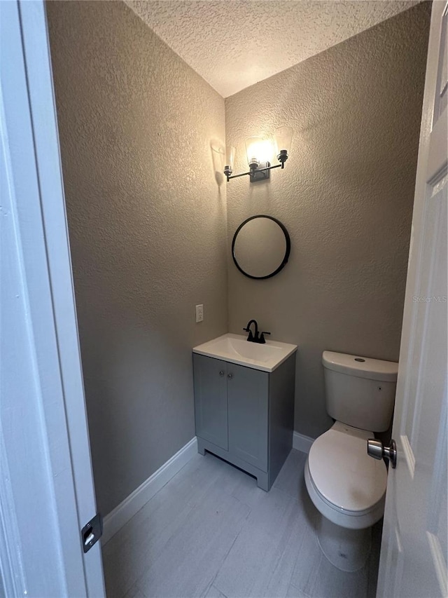 bathroom featuring vanity, a textured ceiling, and toilet