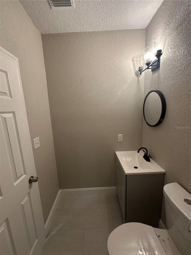 bathroom featuring vanity, a textured ceiling, tile floors, and toilet